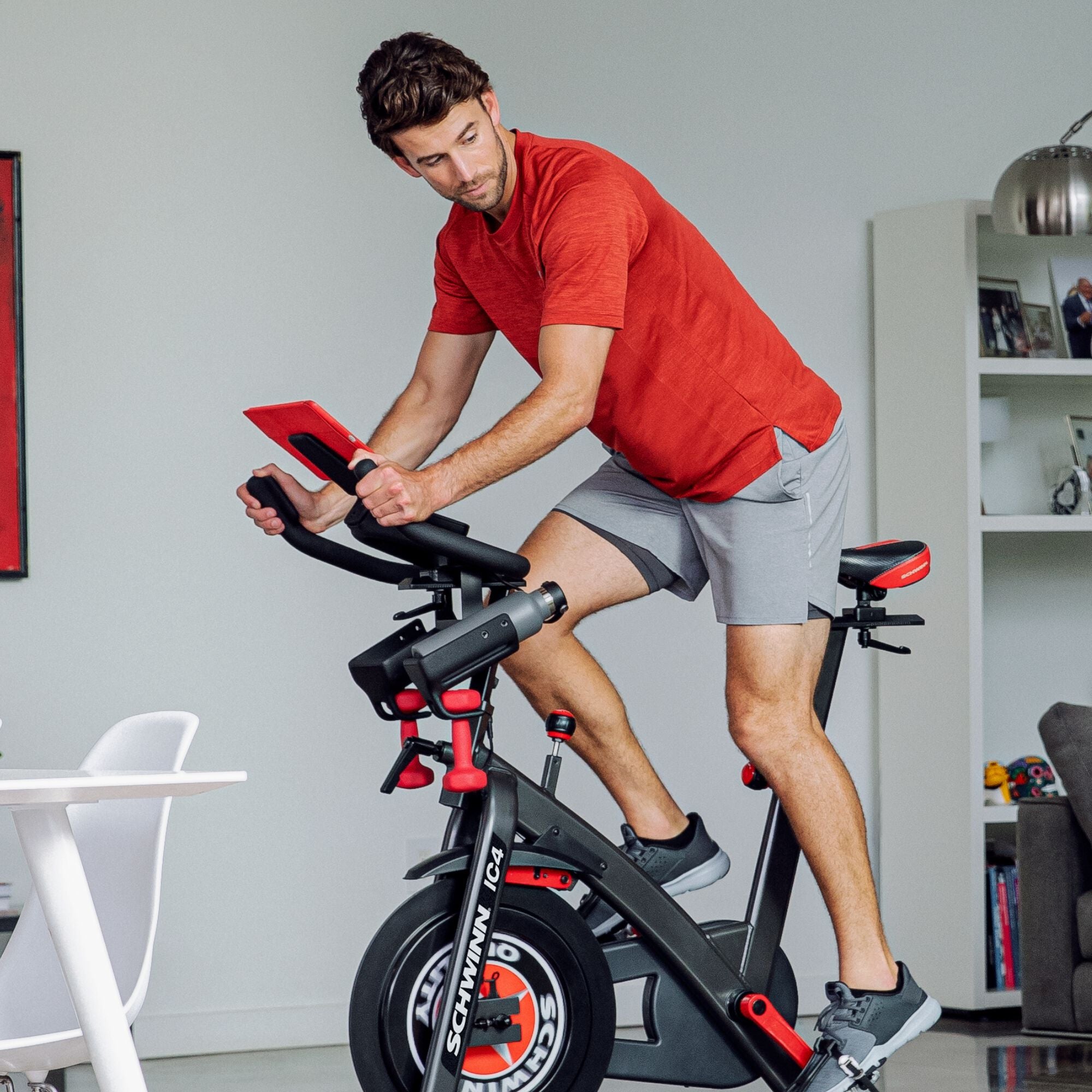 A rider in a red shirt cycling on a Schwinn IC4 with a tablet mounted on the handlebar